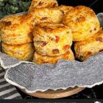 Bacon cheddar biscuits stacked in a towel lined bread basket.