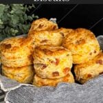 Bacon cheddar biscuits stacked in a towel lined bread basket.