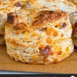 Bacon cheddar biscuits on a parchment paper lined baking sheet.