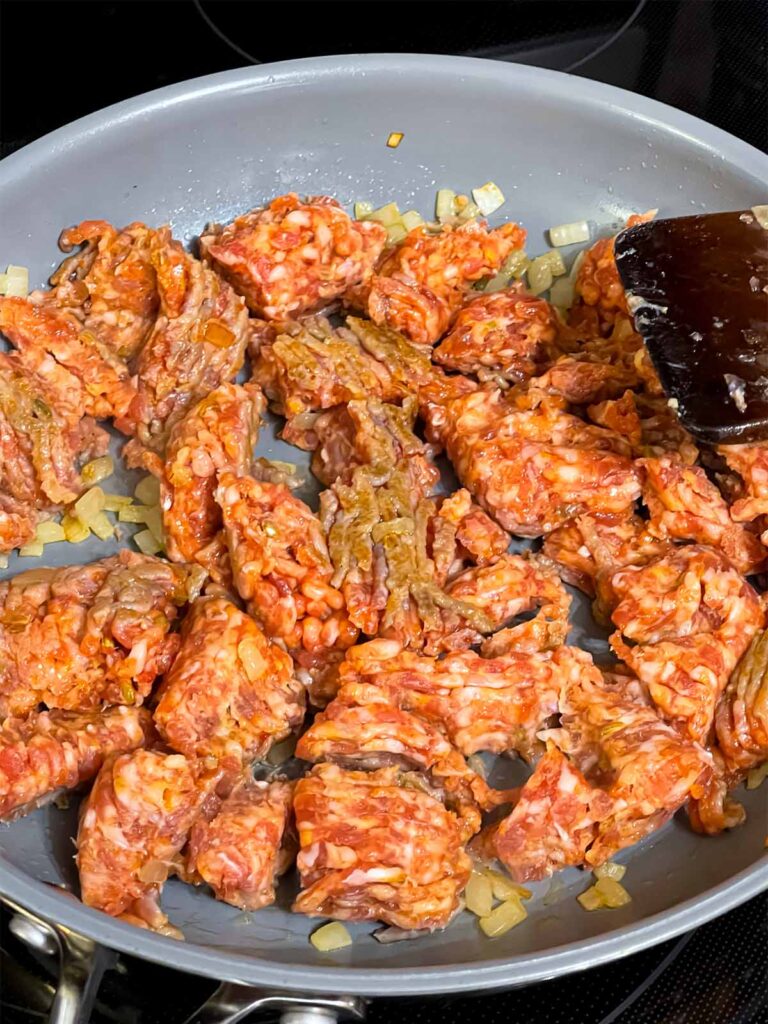 Italian sausage cooking in a skillet.