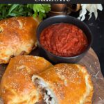 A calzone on a cutting board with a dipping sauce.