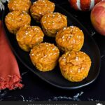 Pumpkin apple muffins on a dark oval platter.