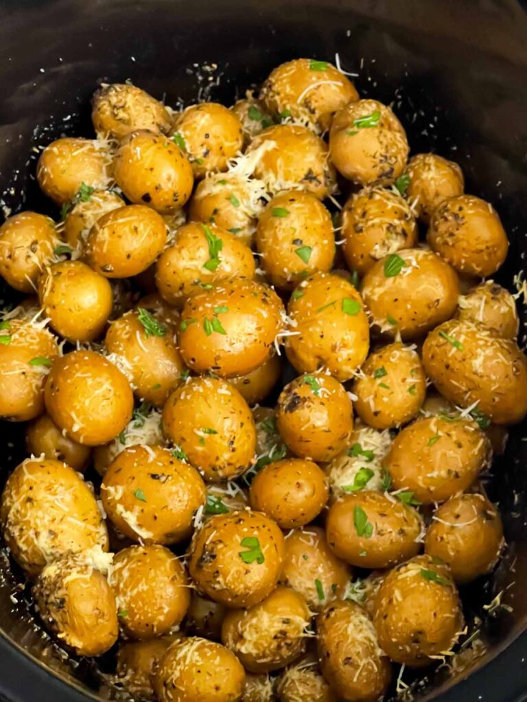 Cooked garlic parmesan potatoes in the crock of a slow cooker.