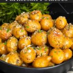 Slow cooker garlic parmesan potatoes in a dark bowl garnished with parsley and parmesan cheese.