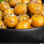 Slow cooker garlic parmesan potatoes in a dark bowl garnished with parsley and parmesan cheese.