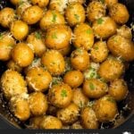 Slow cooker garlic parmesan potatoes in the crock garnished with parsley and parmesan cheese.