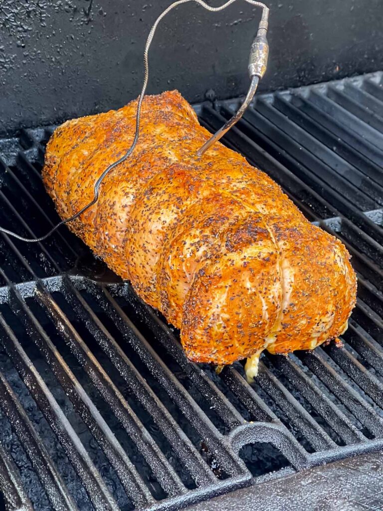 A Texas style smoked pork loin on a smoker with a temperature probe inserted.