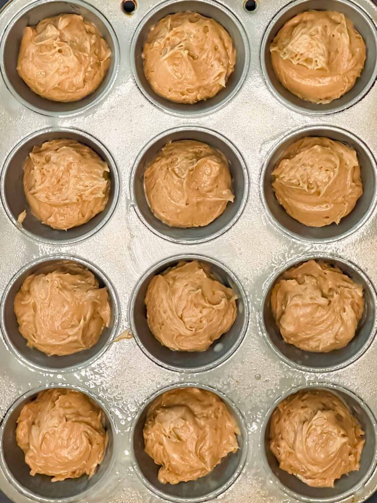 Apple cider muffins batter divided into a 12 cup muffin pan.