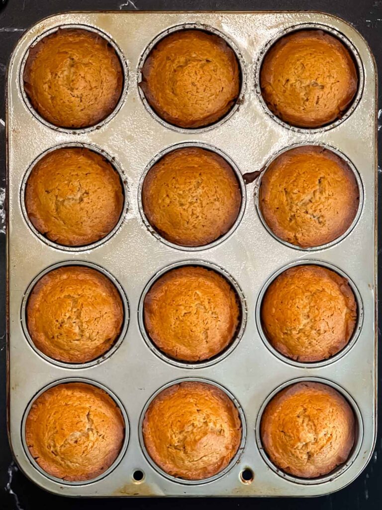 Baked apple cider muffins in the muffin tin.