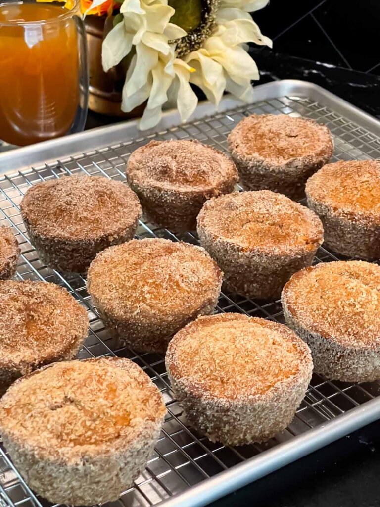 Apple cider muffins on a wire rack over a baking sheet.