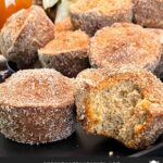 Apple cider muffins stacked on a dark plate.