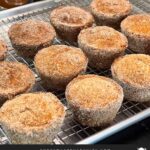 Apple cider muffins on a wire rack over a baking sheet.