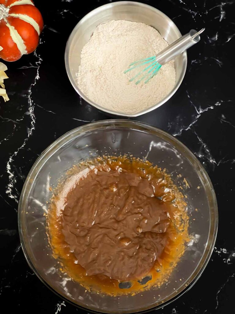 Baked pumpkin donuts wet batter in a glass bowl and dry ingredients in a metal bowl.