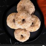 Baked pumpkin donuts stacked on a stacked on a dark plate.