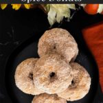 Baked pumpkin donuts stacked on a stacked on a dark plate.