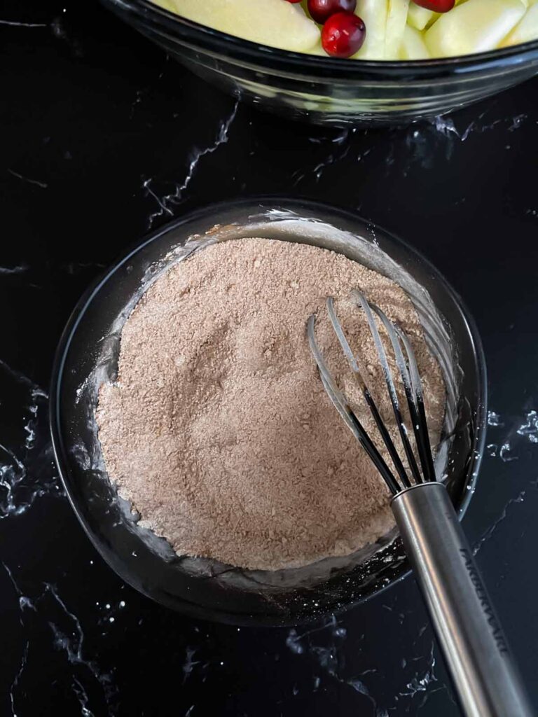 Cranberry apple pie filling dry ingredients mixed in a dark bowl.