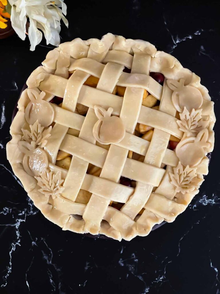 Unbaked cranberry apple pie on a dark surface.