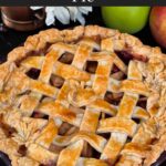 Whole cranberry apple pie on a dark surface.