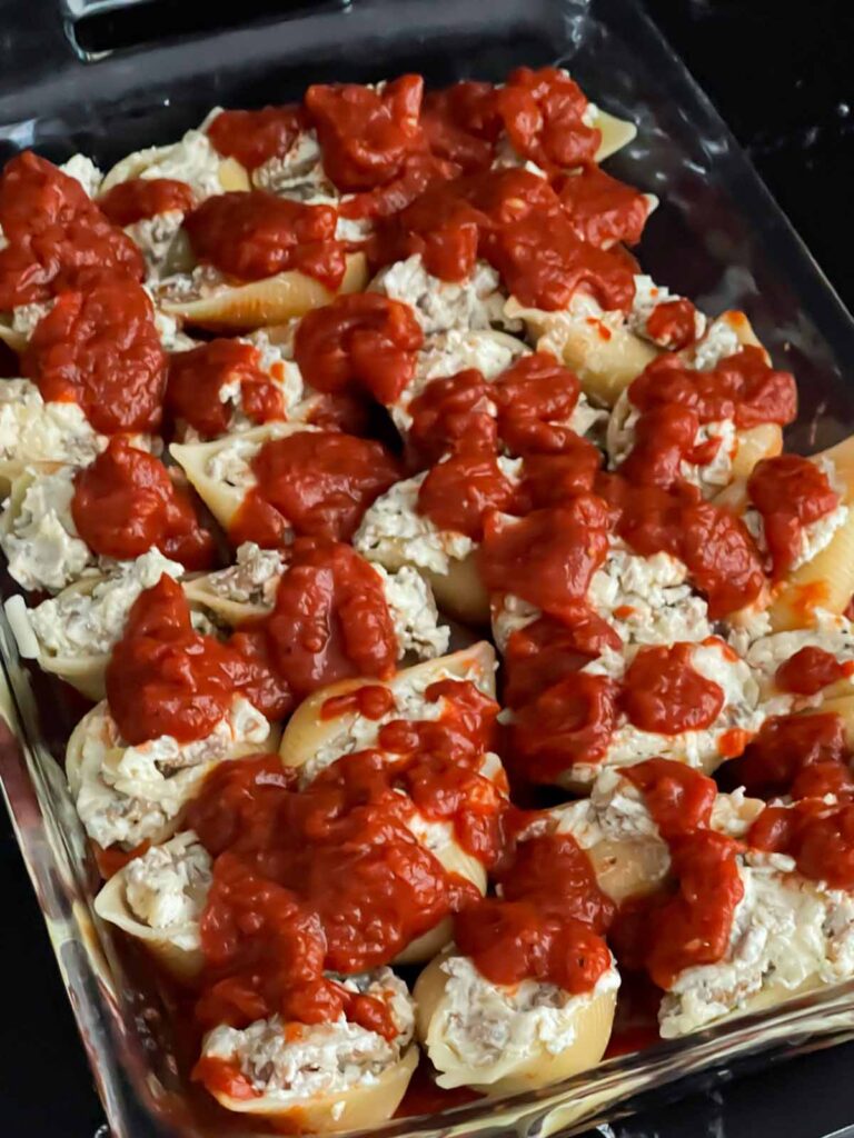 Unbaked Italian sausage stuffed shells with marinara sauce on top.