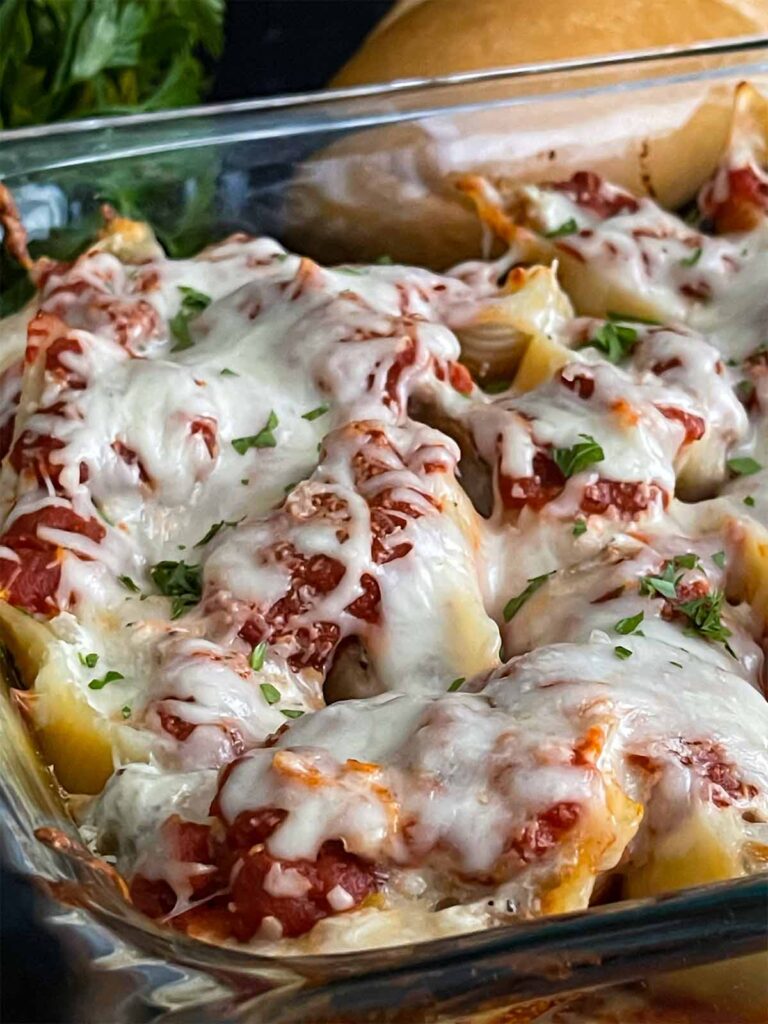 Italian sausage stuffed shells with bread in the background.