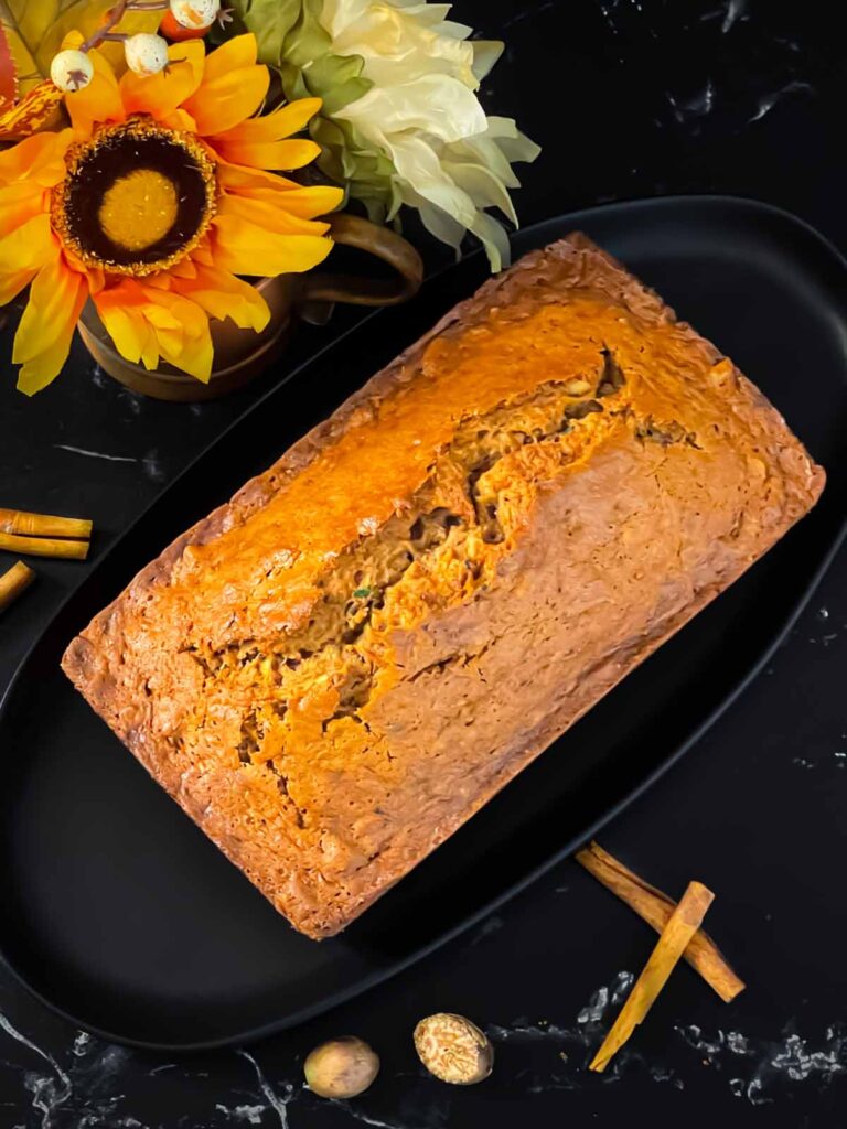 Zucchini bread loaf on a dark oval platter on a dark surface.