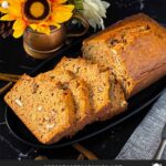 Sliced zucchini bread loaf on a dark oval platter on a dark surface.