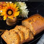 Sliced zucchini bread loaf on a dark oval platter on a dark surface.