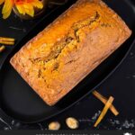 Zucchini bread loaf on a dark oval platter on a dark surface.