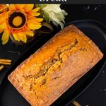 Zucchini bread loaf on a dark oval platter on a dark surface.