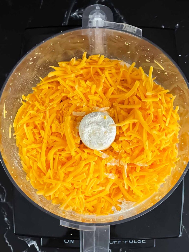 Shredded cheddar cheese in a food processor.