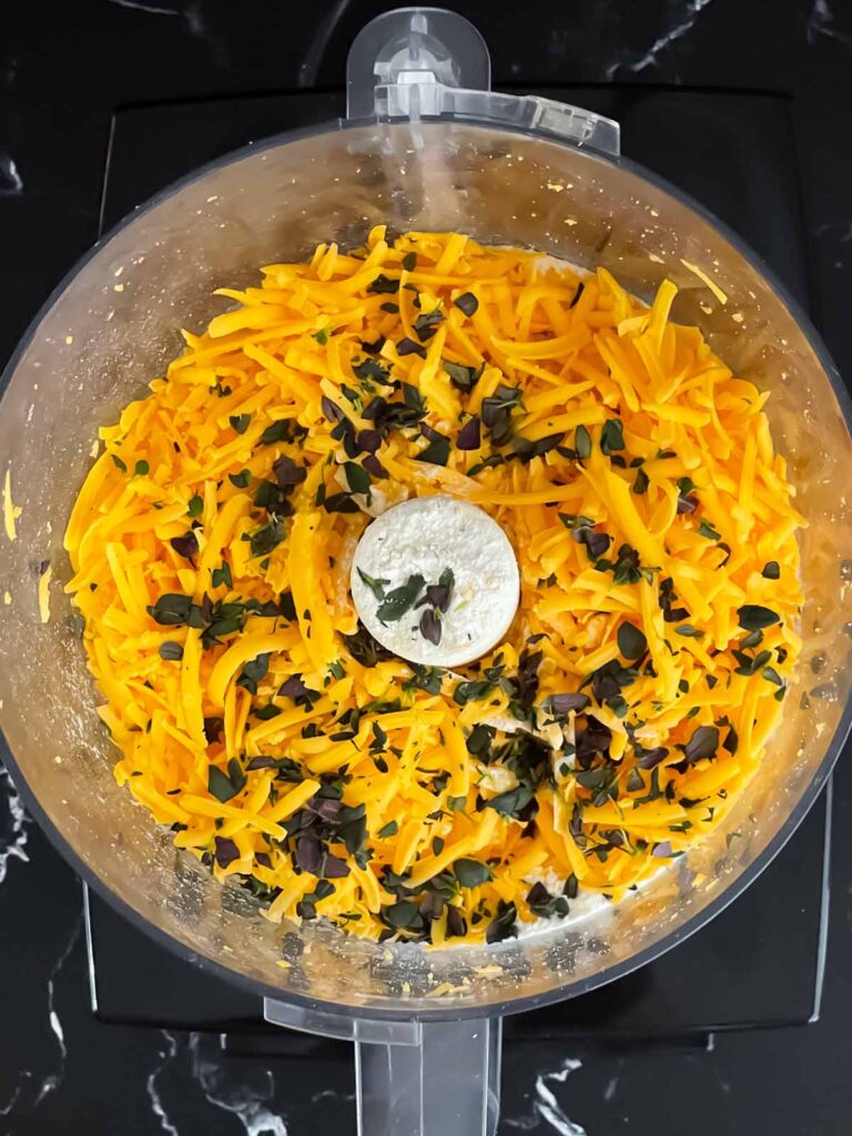 Grated cheddar cheese and herbs in a food processor.