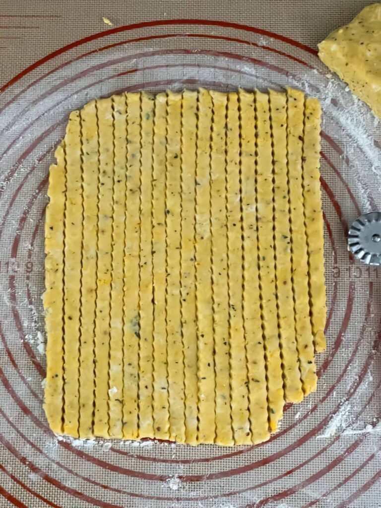 Cheese straw dough on a dough mat, cut into straws.