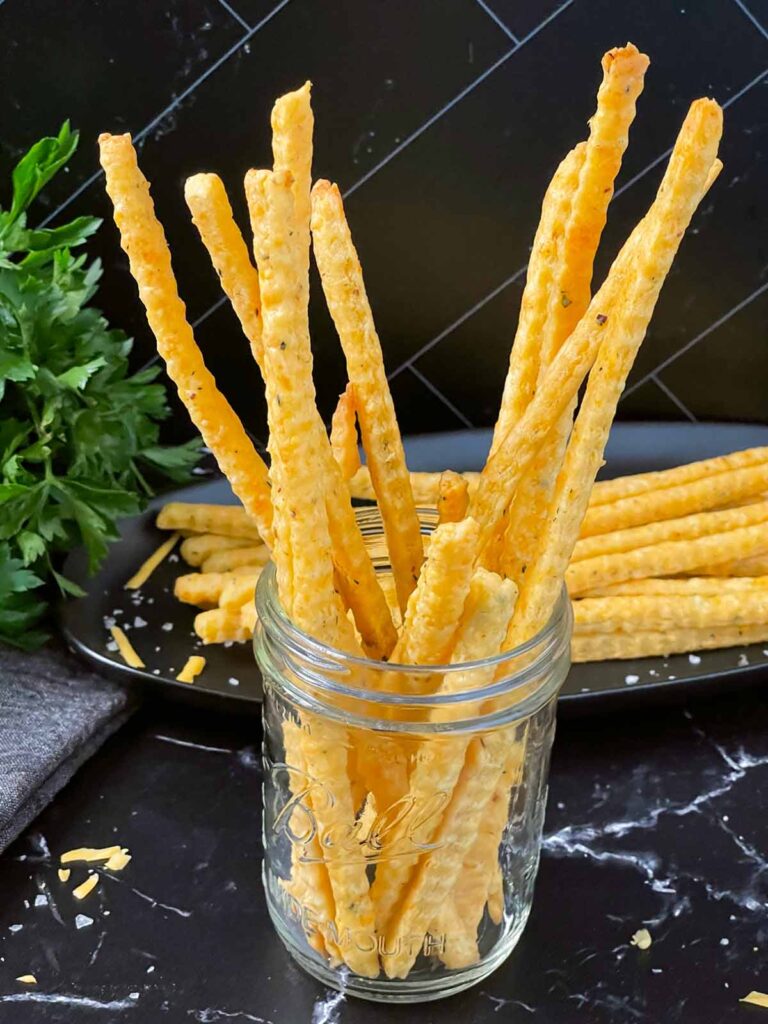 Cheddar and herb cheese straws in a mason jar.