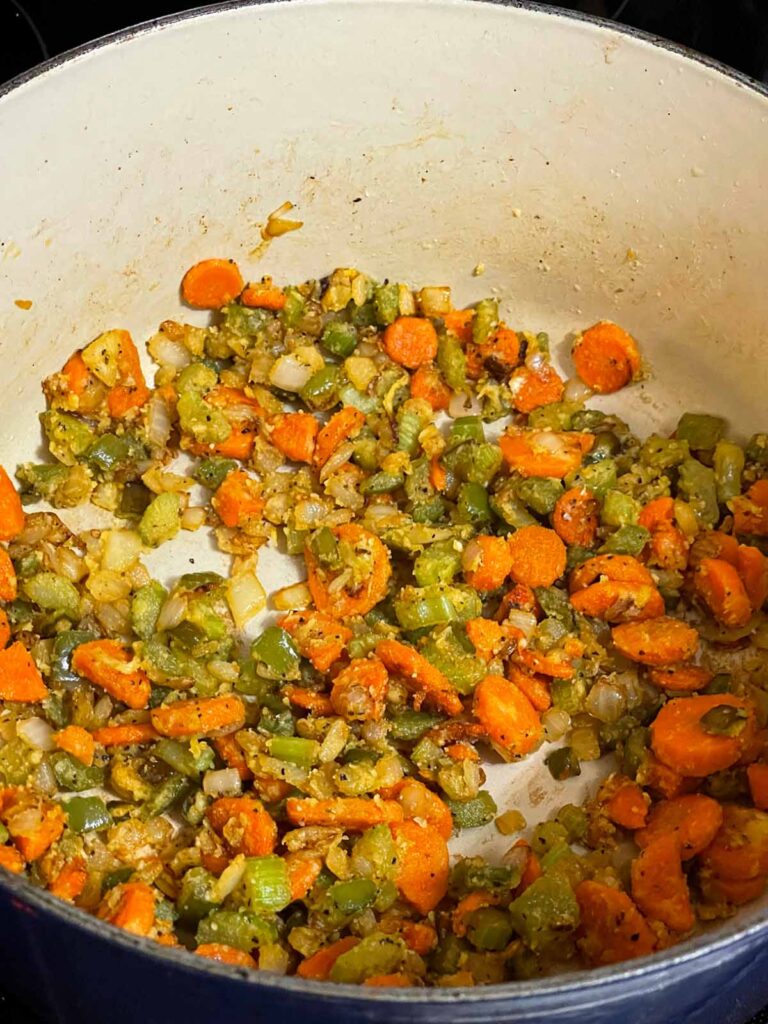 Adding flour to cooked vegetables in a dutch oven.