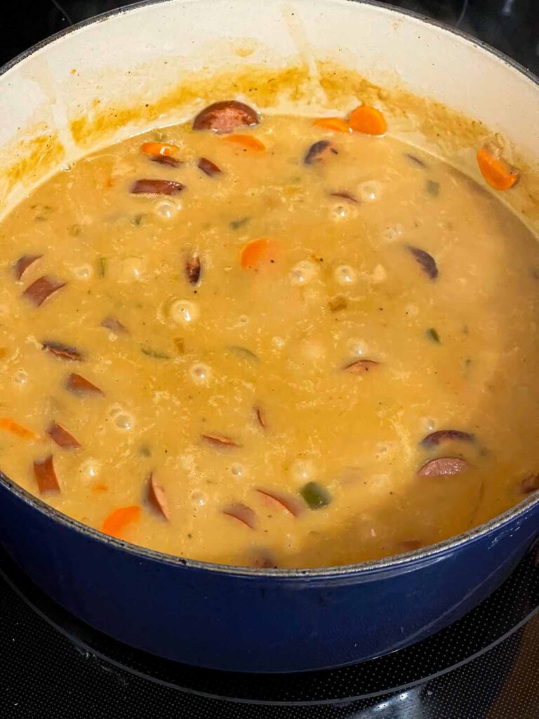 Bean soup with smoked sausage cooking in a dutch oven.