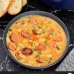 Bean soups with smoked sausage with bread and parsley in the background.