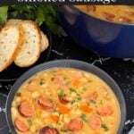 Bean soups with smoked sausage with bread and parsley in the background.