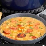 Bean soups with smoked sausage with bread and parsley in the background.