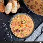 Bean soups with smoked sausage with bread and parsley in the background.