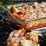 Italian sausage stuffed shells in a casserole dish with a serving on a black plate.