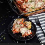 Italian sausage stuffed shells in a casserole dish with a serving on a black plate.