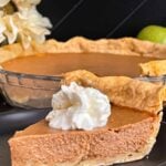 Apple butter pie with a sliced on a dark plate, garnished with whipped cream.