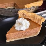 Apple butter pie with a sliced on a dark plate, garnished with whipped cream.