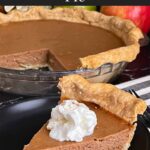 Apple butter pie with a sliced on a dark plate, garnished with whipped cream.