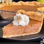 Apple butter pie with a sliced on a dark plate, garnished with whipped cream.