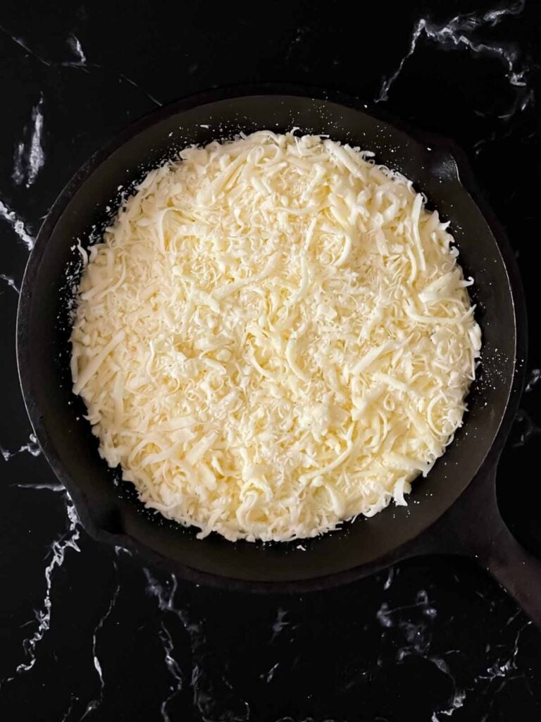 Ricotta dip topped with a cheese blend in a cast iron skillet.