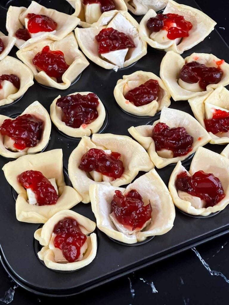 Unbaked cranberry brie bites in a mini muffin tin.