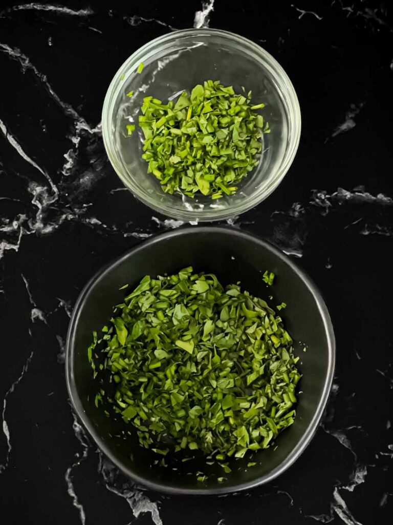 Chopped herbs in black bowls.