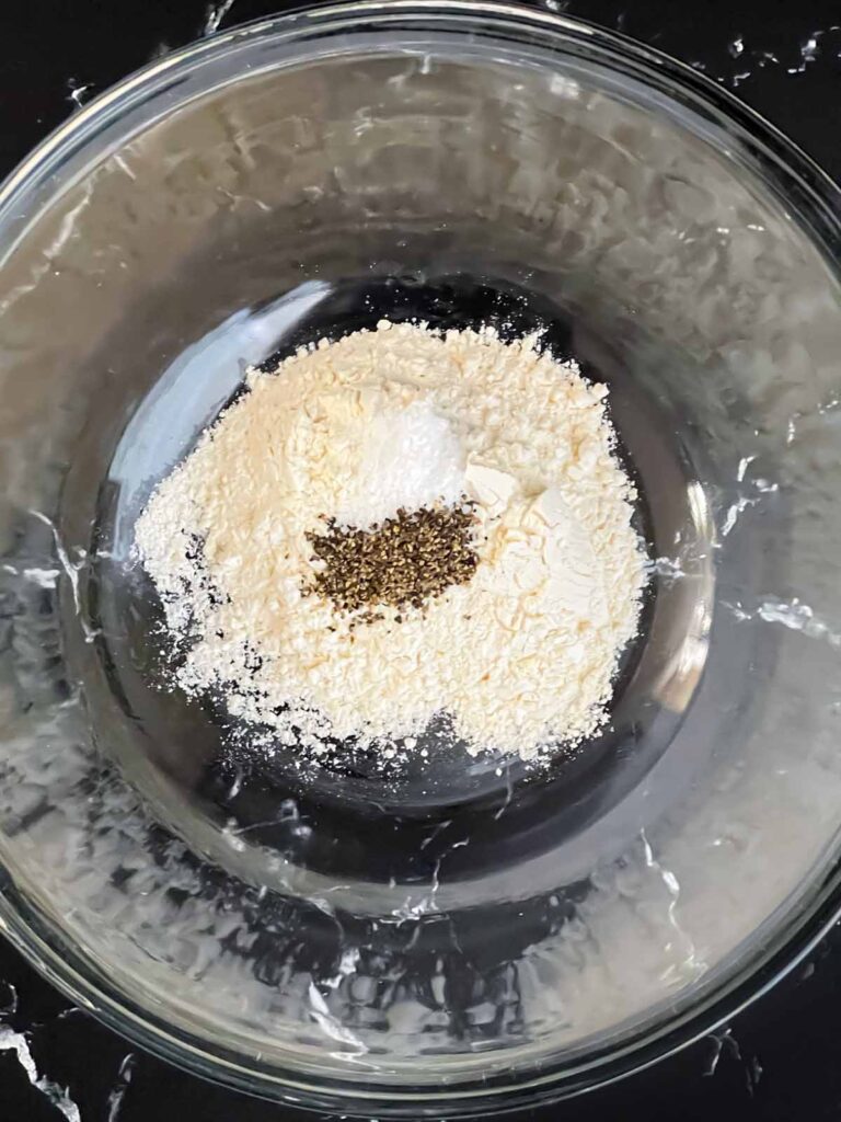 Flour, salt, and pepper in a glass bowl.