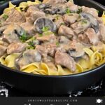 Slow Cooker Beef Stroganoff in a black bowl, garnished with chopped parsley.